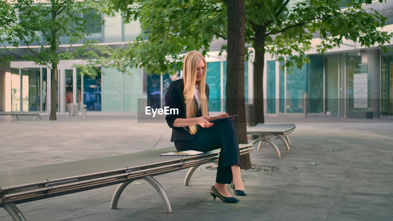 side view of woman sitting on bench in park