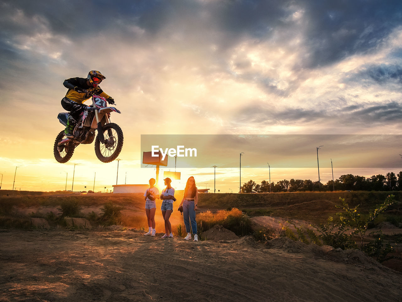 PEOPLE ON MOTORCYCLE ON FIELD AGAINST SKY