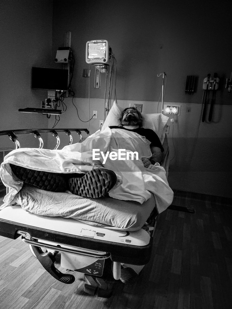 white, black and white, monochrome photography, indoors, black, monochrome, bed, healthcare and medicine, hospital, medical equipment, adult, lying down, furniture, sitting, one person, men, hospital gurney