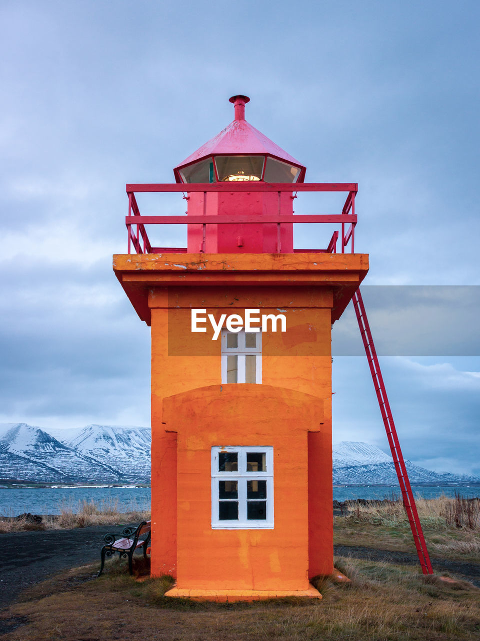 Orange lighthouse in eyjafjörður fjord in northern iceland in winter near the town of akureyri