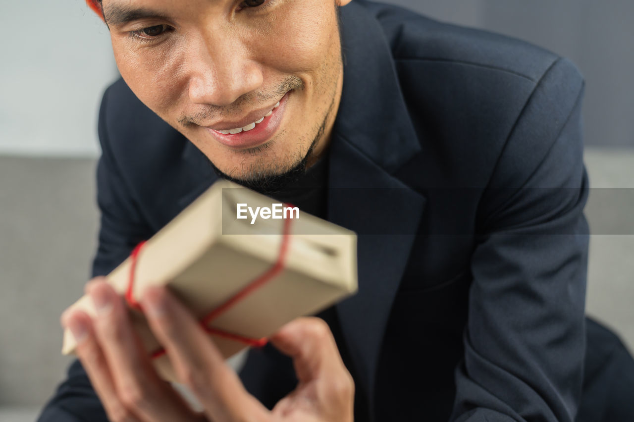 PORTRAIT OF MAN HOLDING CAMERA IN OFFICE