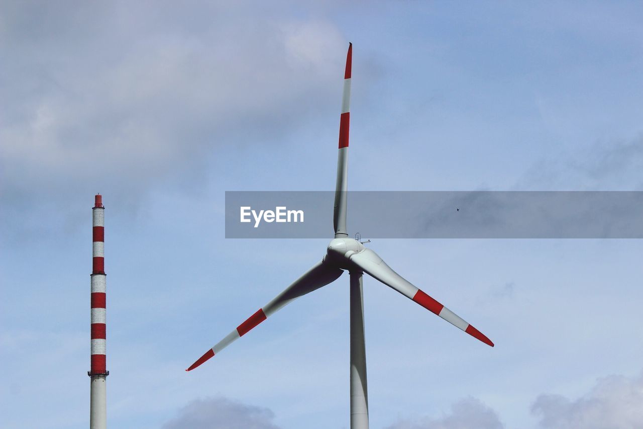 Low angle view of wind turbine and smoke stack