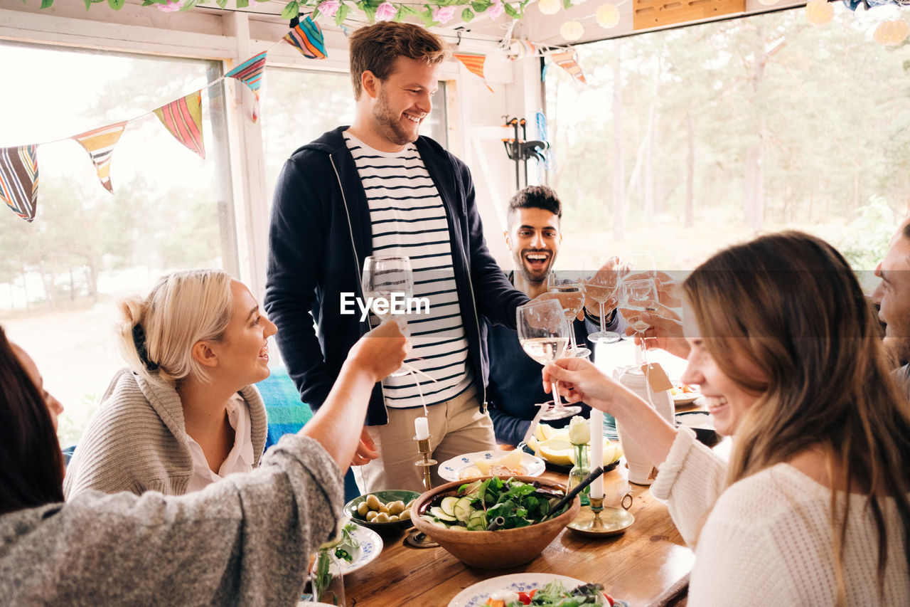 Happy man toasting wineglass with friends during lunch party