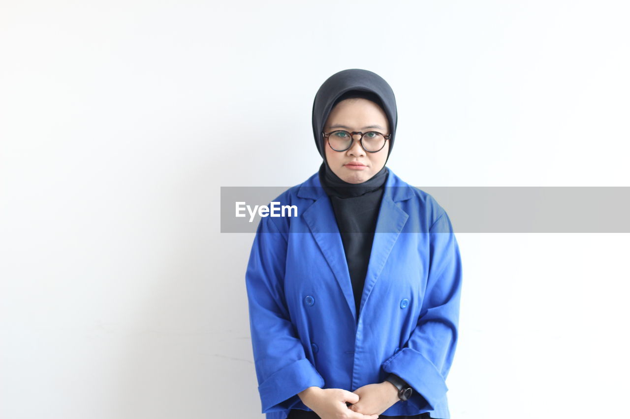 outerwear, one person, sleeve, adult, portrait, indoors, studio shot, clothing, looking at camera, white background, front view, hood, young adult, copy space, waist up, men, jacket, standing, blue, occupation, serious, person, eyeglasses, business, three quarter length, cut out