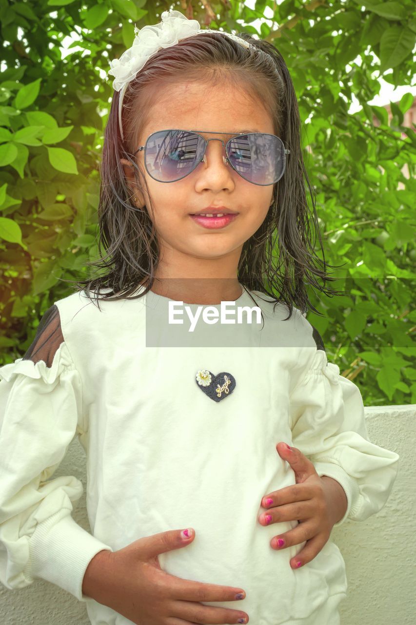 Portrait of girl wearing sunglasses standing against plants