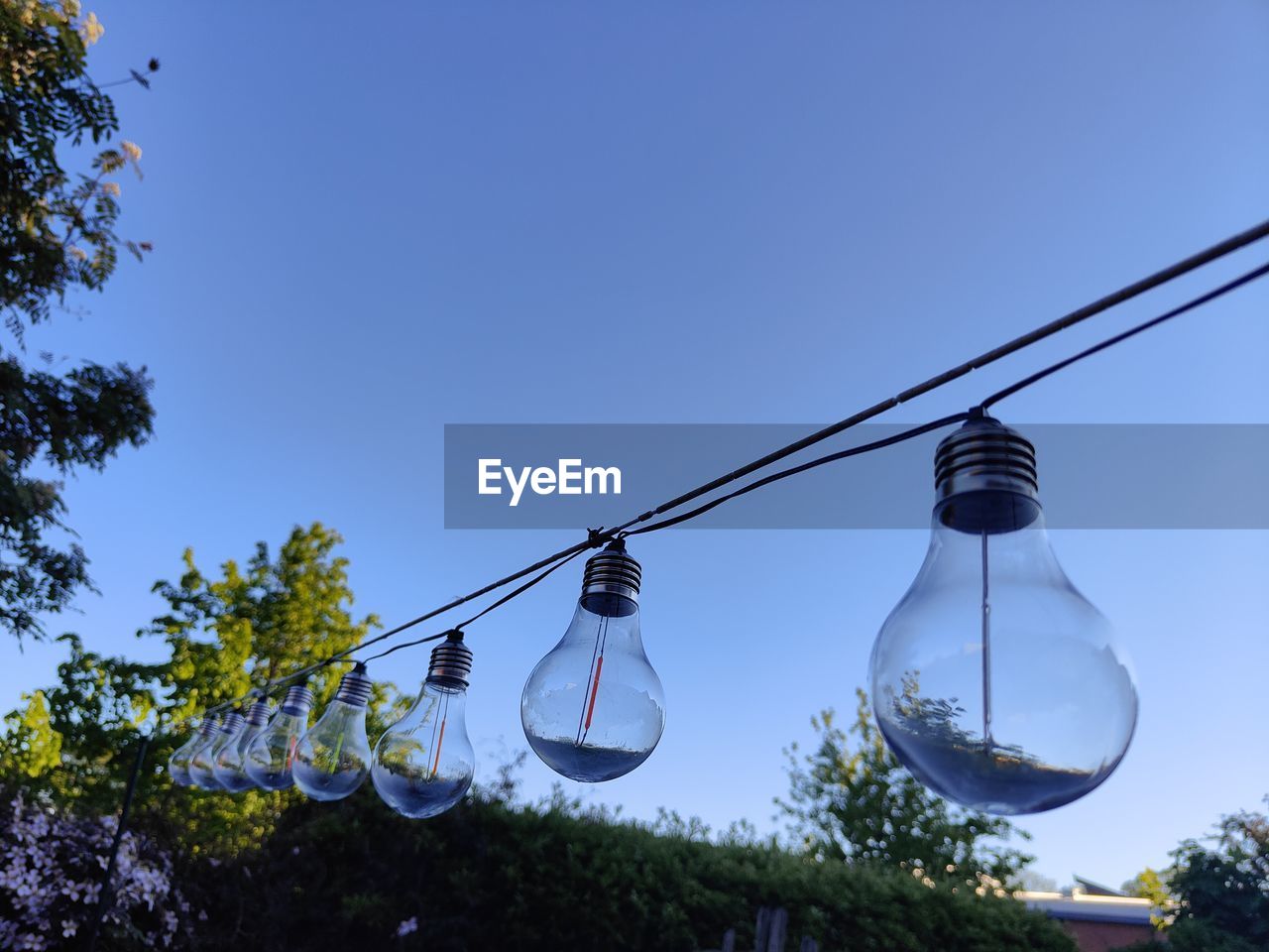 LOW ANGLE VIEW OF LIGHT BULBS HANGING AGAINST SKY