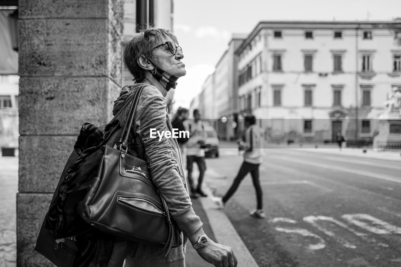 WOMAN STANDING ON STREET AGAINST CITY