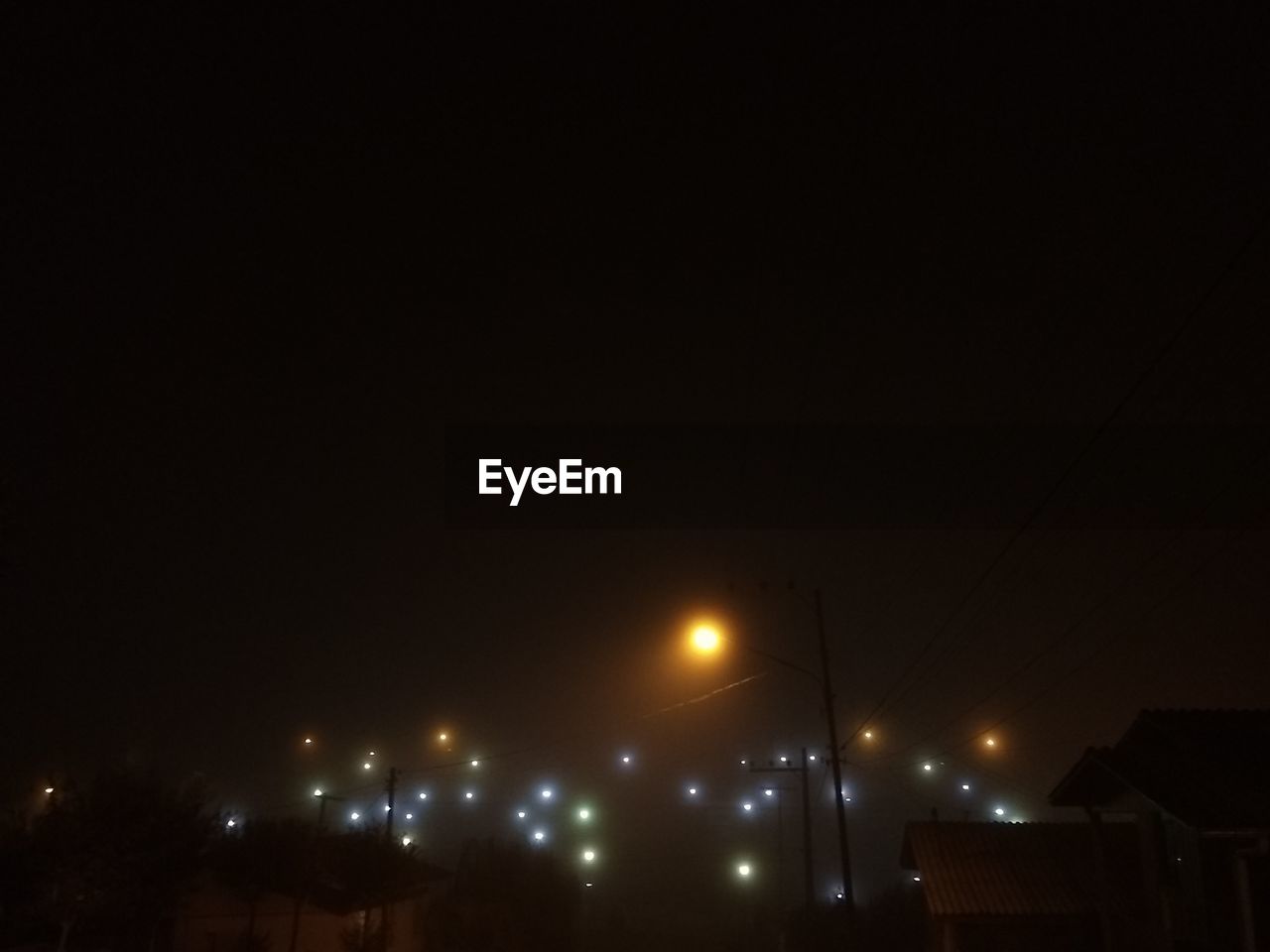 LOW ANGLE VIEW OF ILLUMINATED STREET LIGHT AGAINST BUILDINGS AT NIGHT