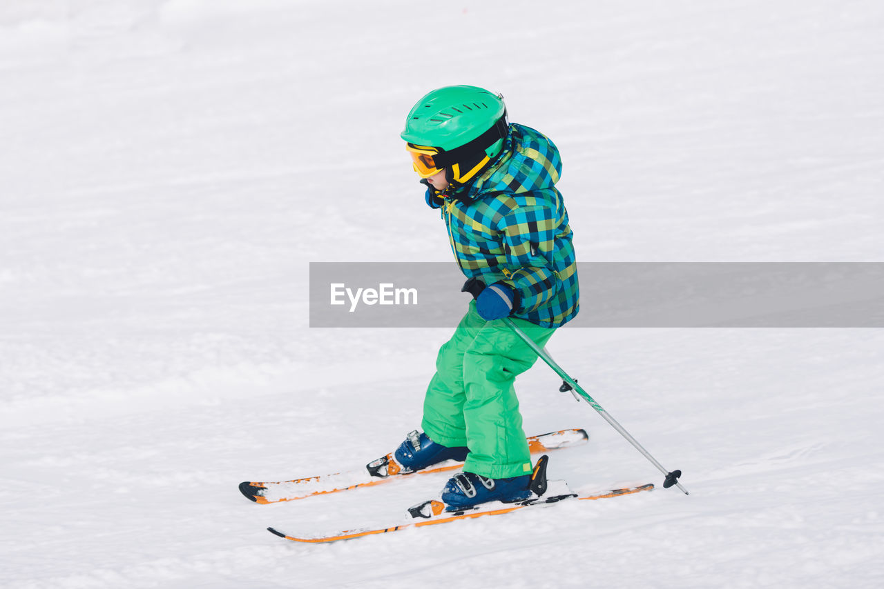 Full length of boy skiing on snow covered land