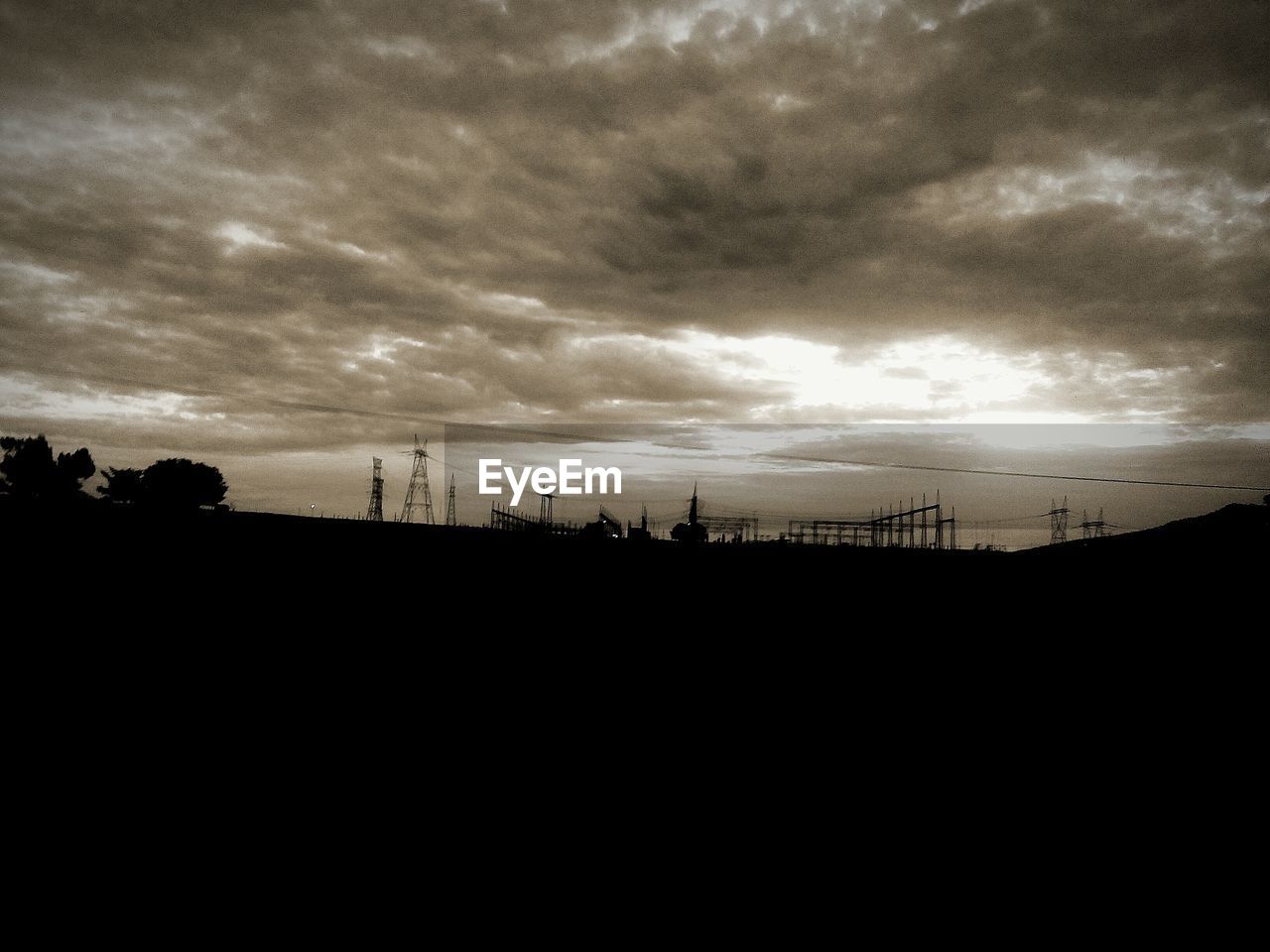 SILHOUETTE OF LANDSCAPE AGAINST CLOUDY SKY AT SUNSET