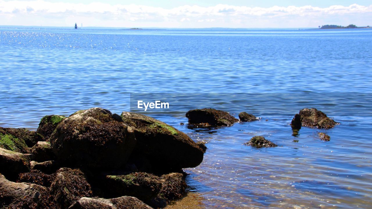 Rocks on sea shore against sky