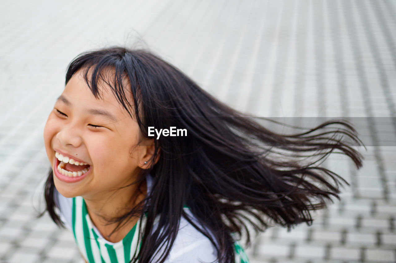 Close-up of girl laughing on footpath