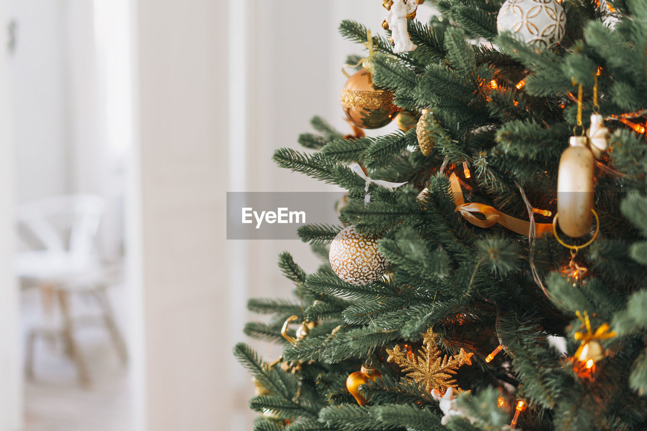 Decorated christmas tree in golden and white toys with lights bokeh textured background