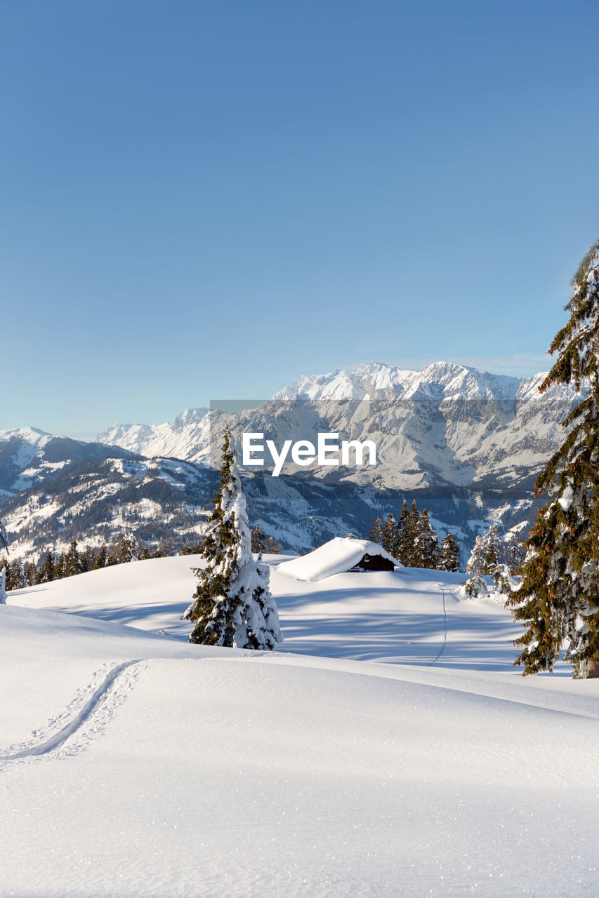 Beautiful winter mountain landscape with snow tracks to the alpine hut