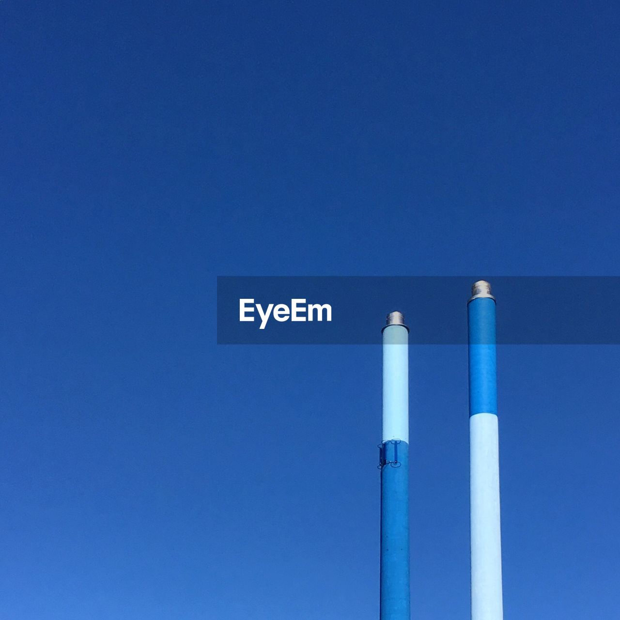 Low angle view of smoke stacks against blue sky