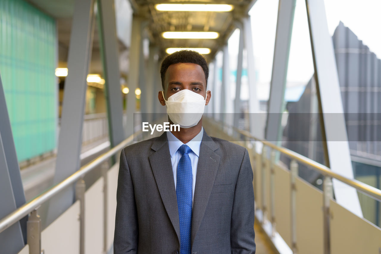 Portrait of young man wearing mask standing on footbridge