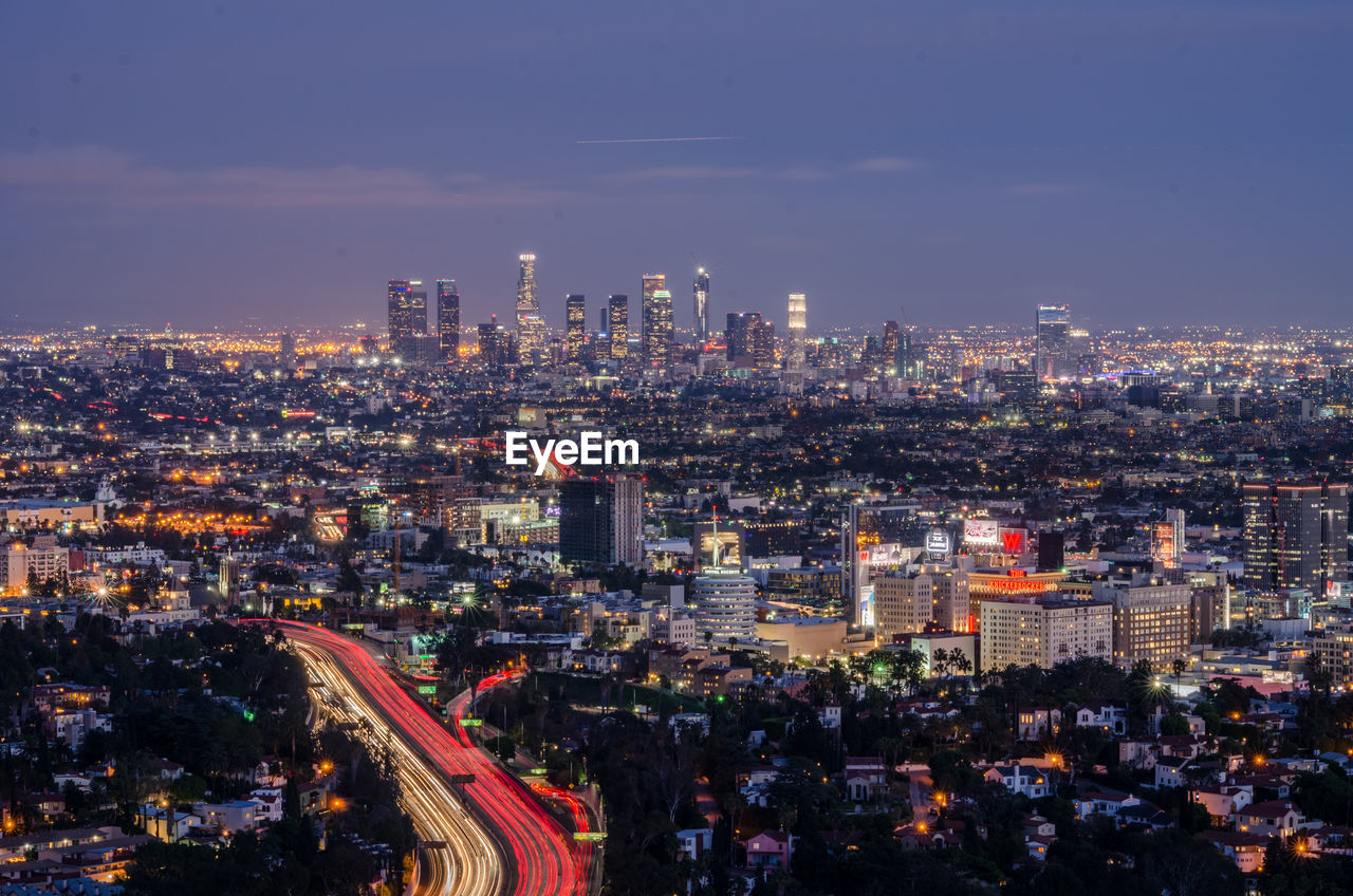 Illuminated cityscape against sky at dusk