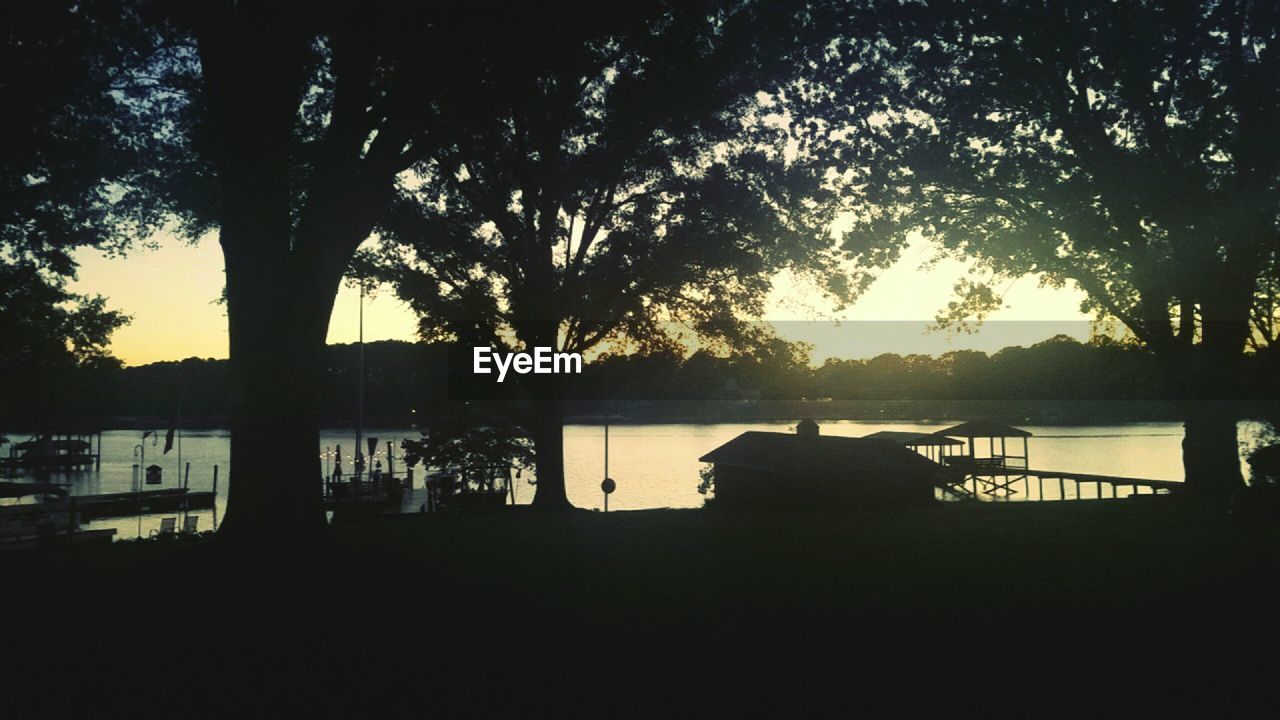 SILHOUETTE TREES BY LAKE AGAINST SKY