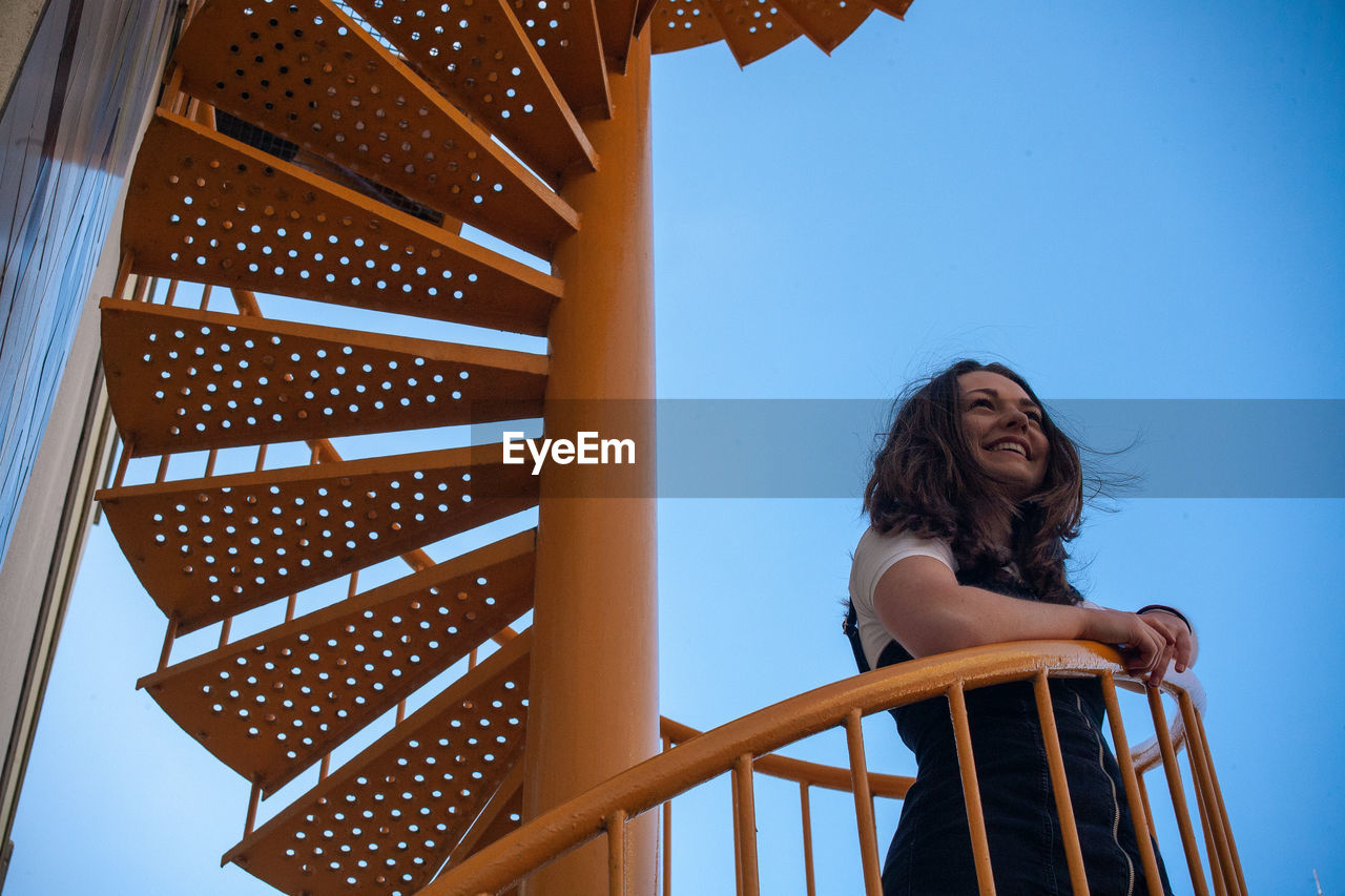 Low angle view of woman standing on steps against sky