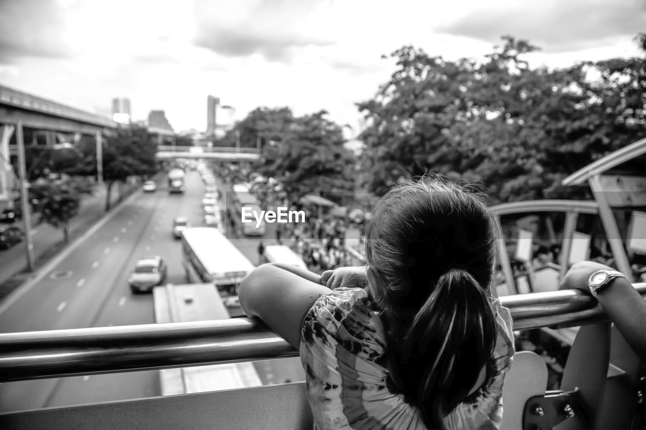 Rear view of girl looking at traffic from bridge