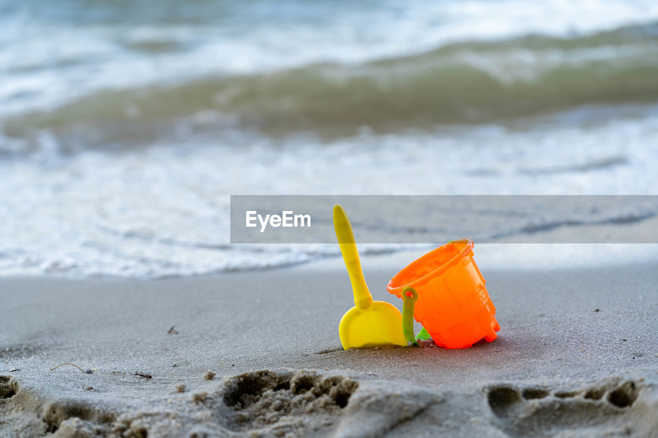 CLOSE-UP OF YELLOW TOY ON SHORE