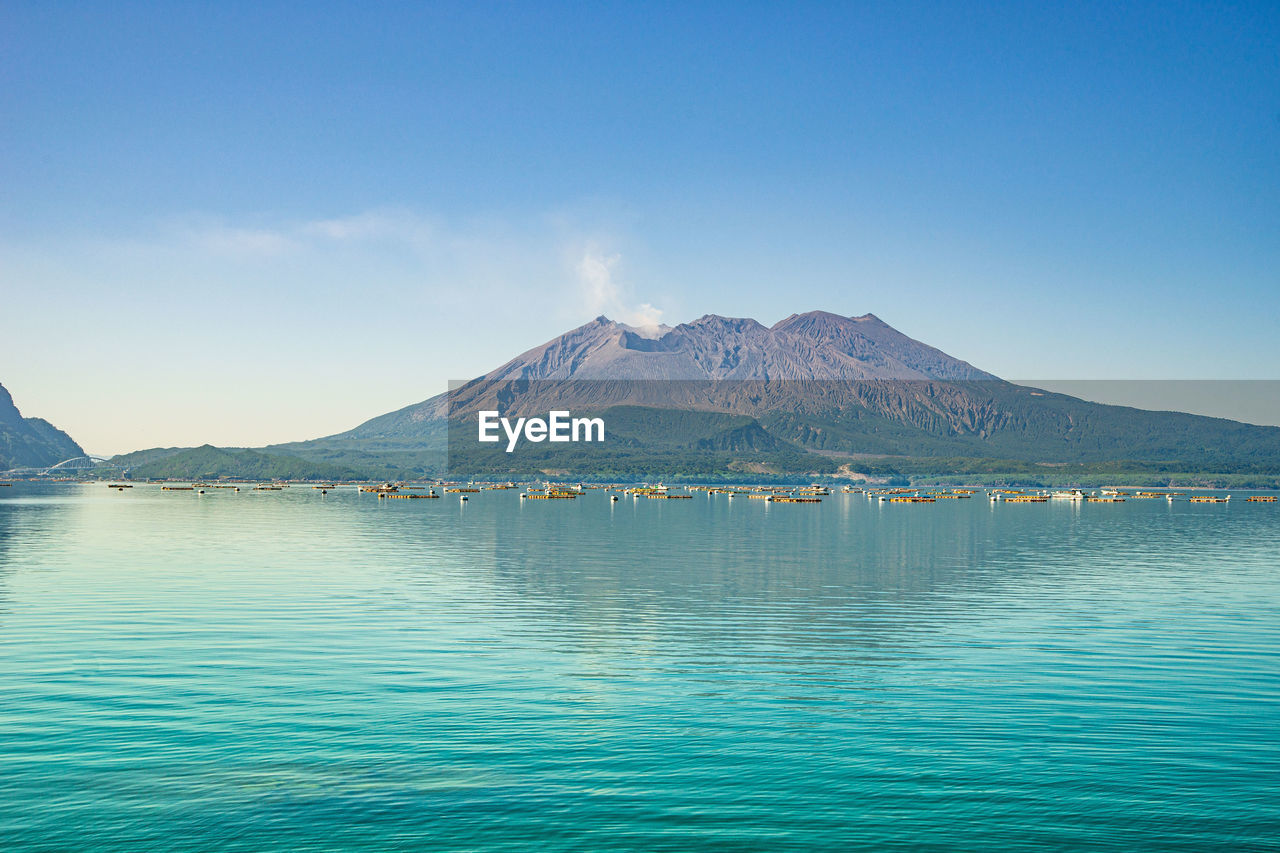 Scenic view of sea and mountains against blue sky