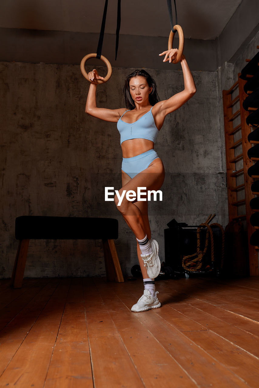 full length of young woman exercising in gym