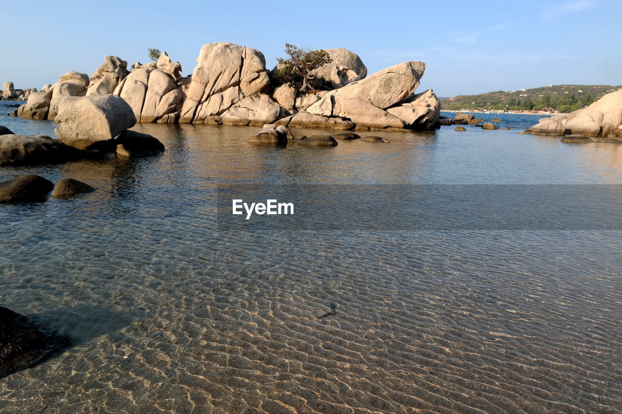 Rock formation on beach against sky