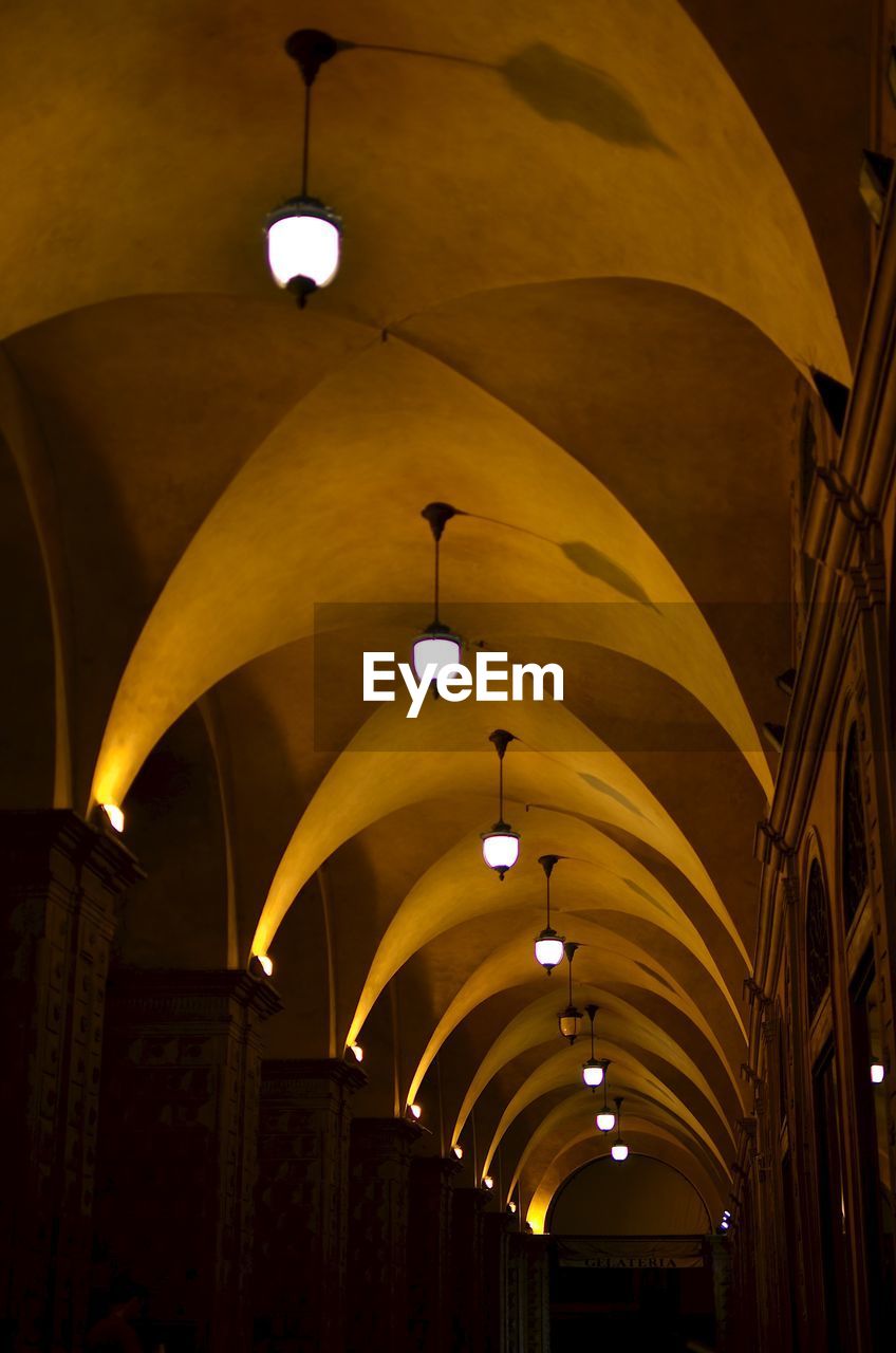 Illuminated pendant lights hanging from ribbed vault ceiling in church