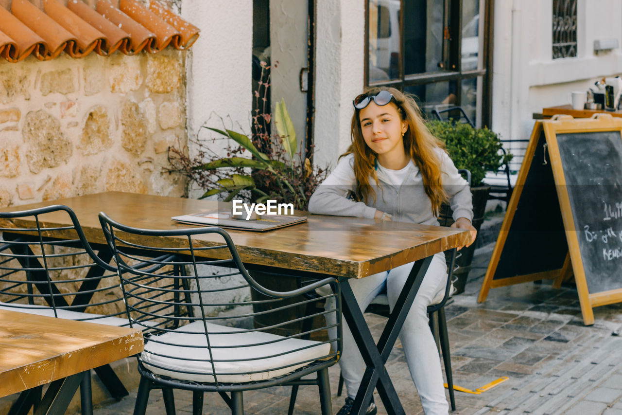 Portrait of girl sitting at table outdoor cafe