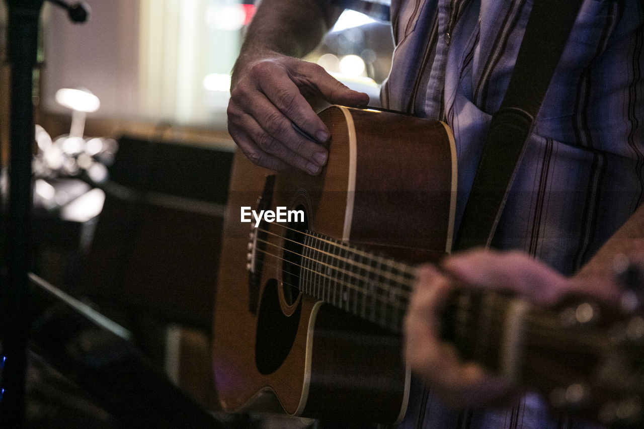 Midsection of man playing guitar
