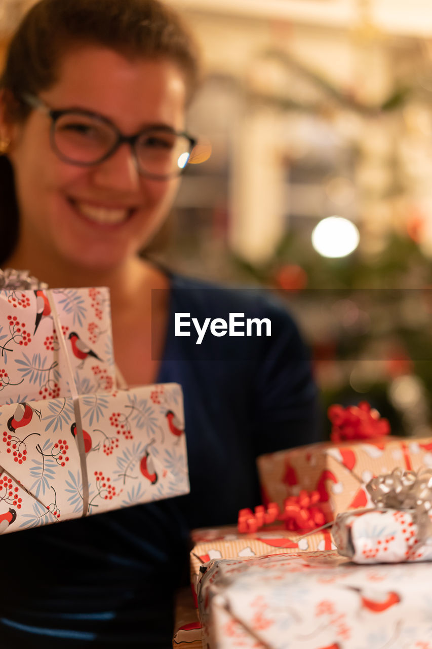 Portrait of a smiling young woman holding christmas gifts