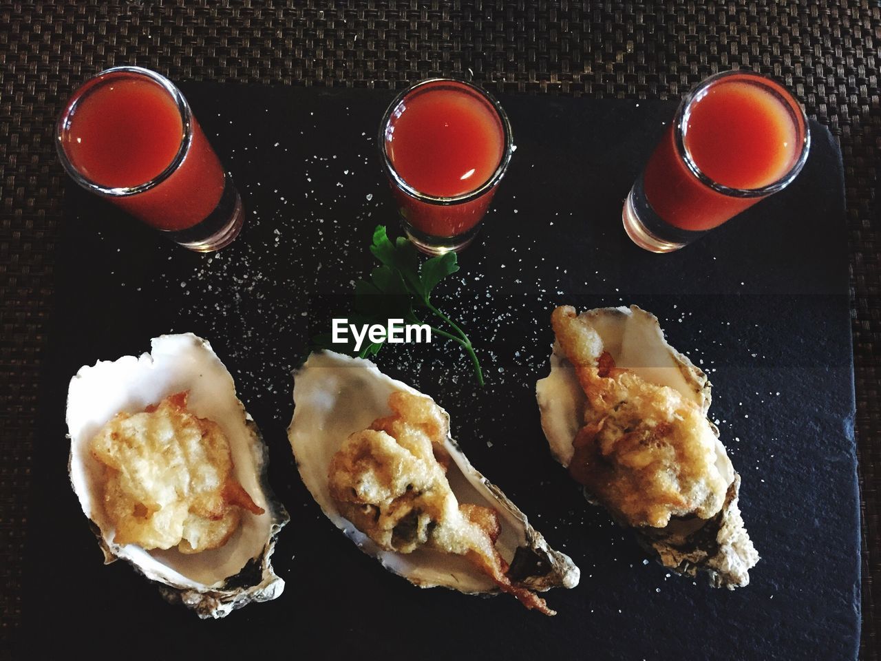 High angle view of oysters and bloody mary sauce on slate