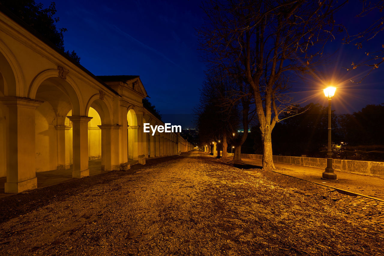 Illuminated street against sky at night