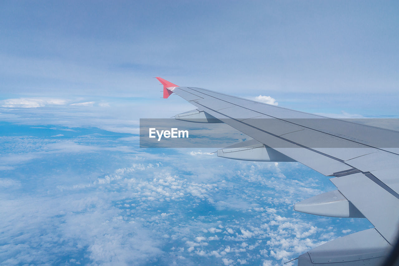 AERIAL VIEW OF AIRPLANE FLYING OVER CLOUDS IN SKY