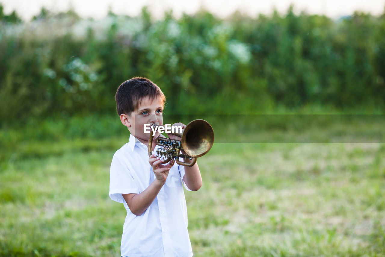 Smiling boy playing trumpet outdoors