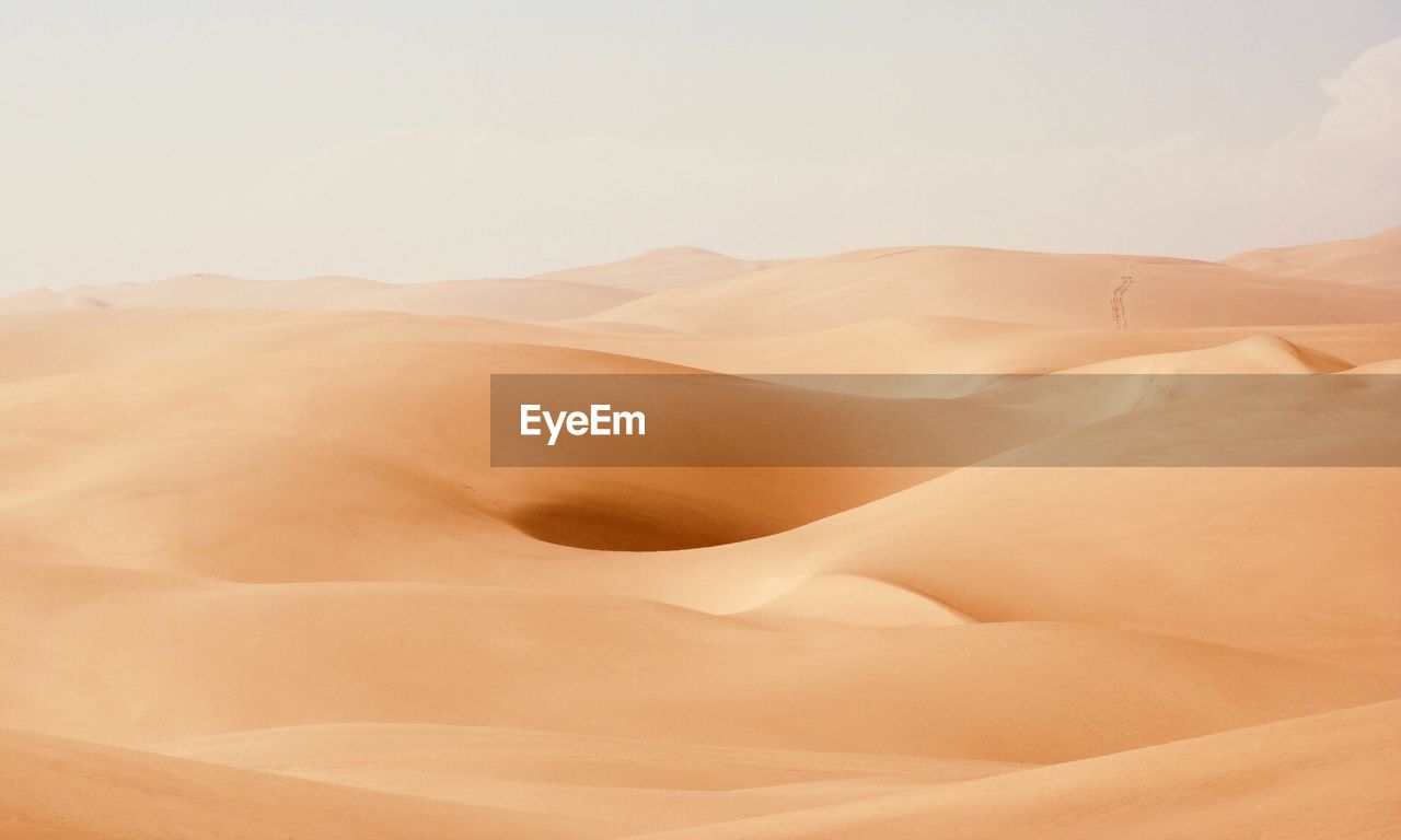 Sand dunes in desert against sky