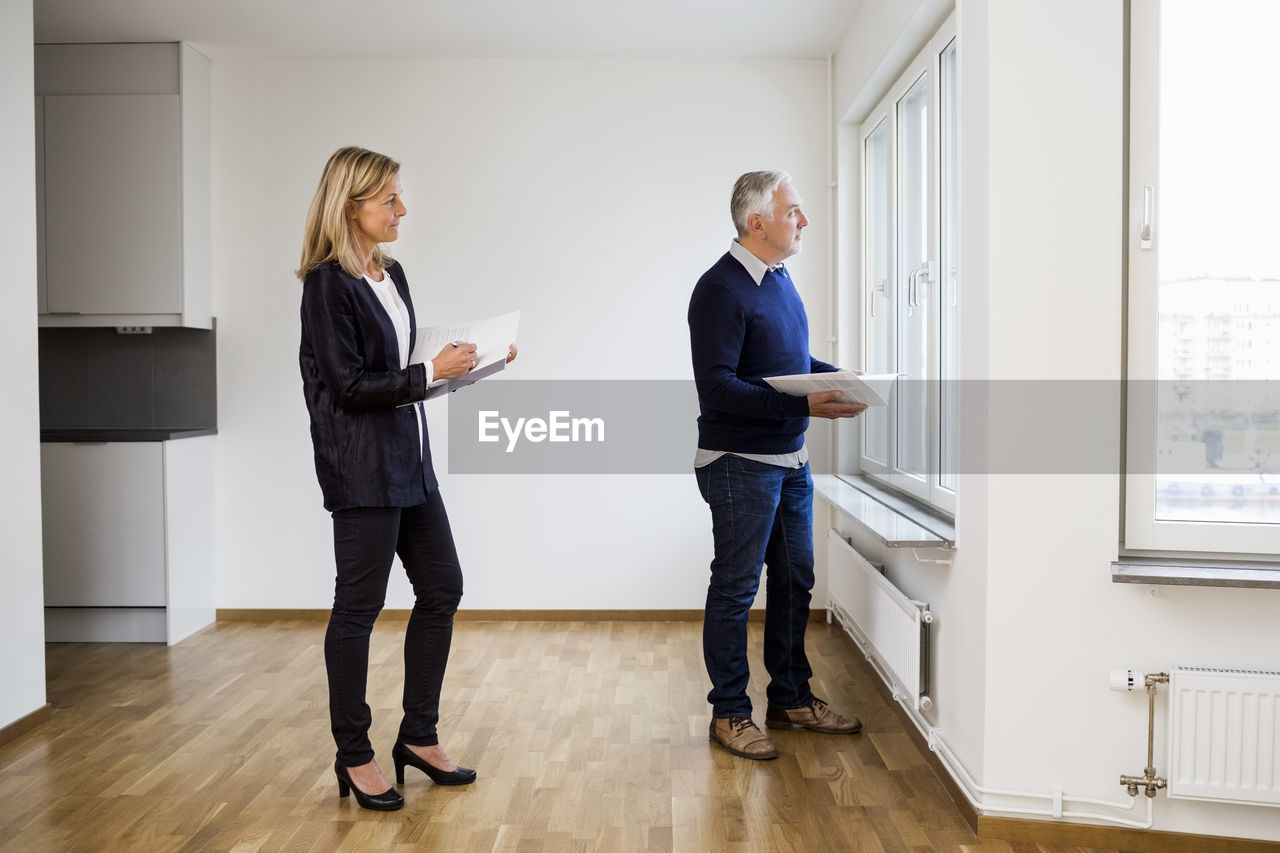 Mature real estate agents looking through window at home