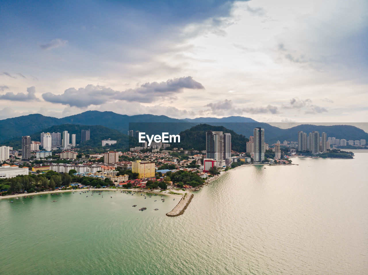 Scenic view of sea by city buildings against sky