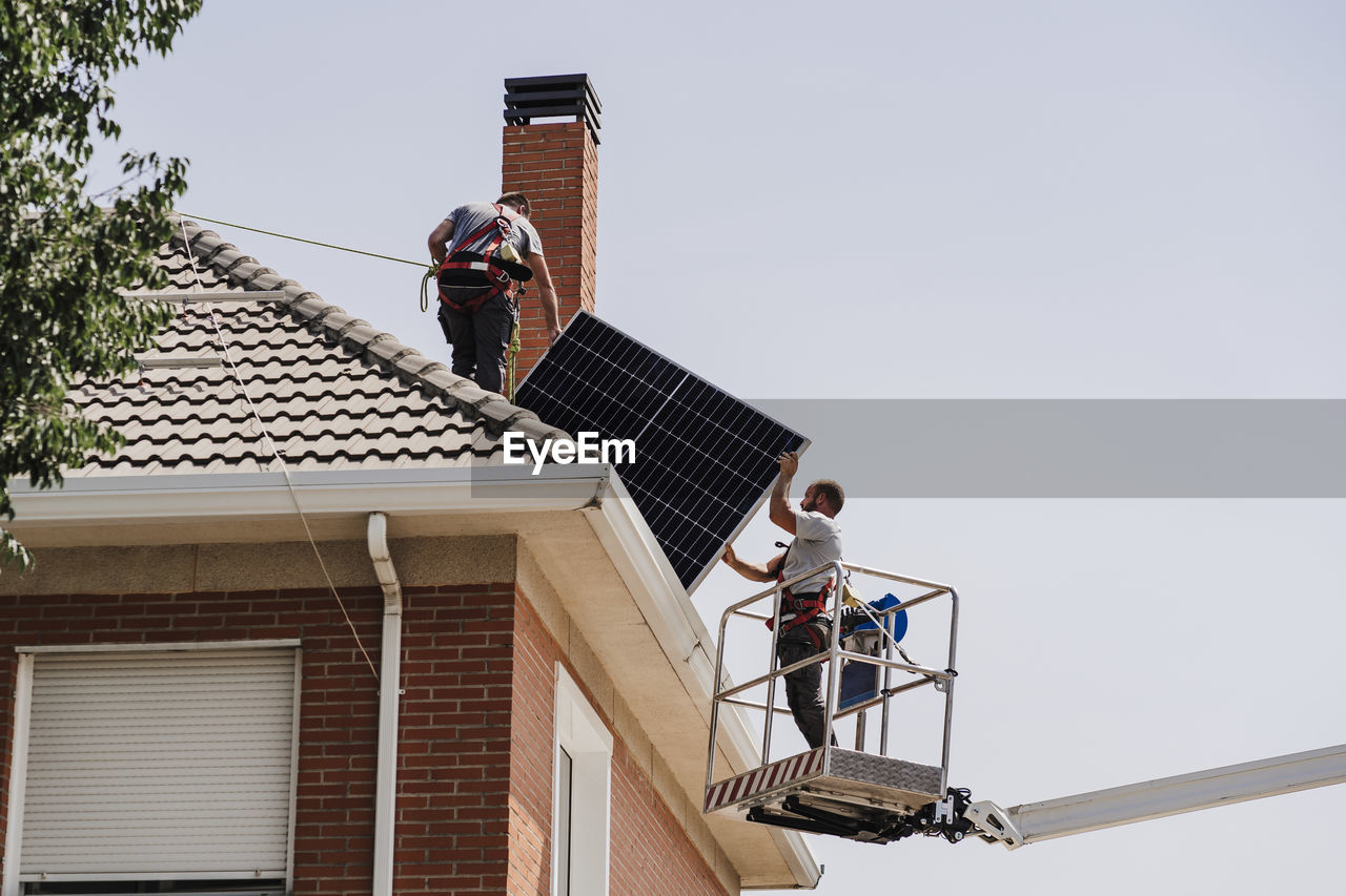 Technicians installing solar panels on rooftop