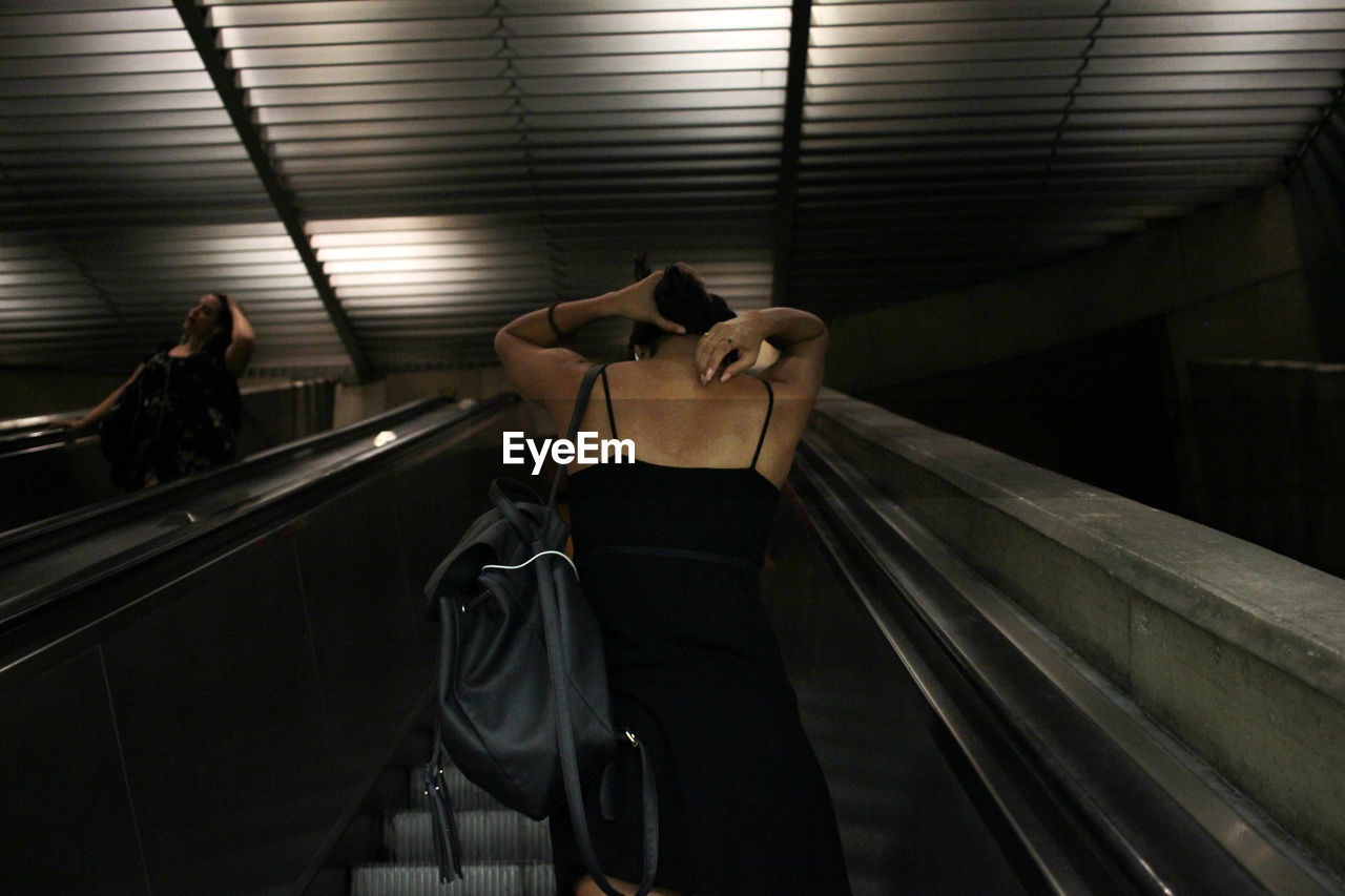 Rear view of woman standing on escalator