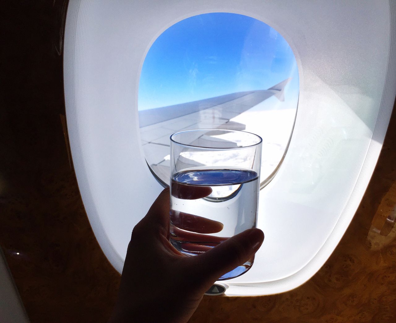 Close-up of woman holding glass by airplane window