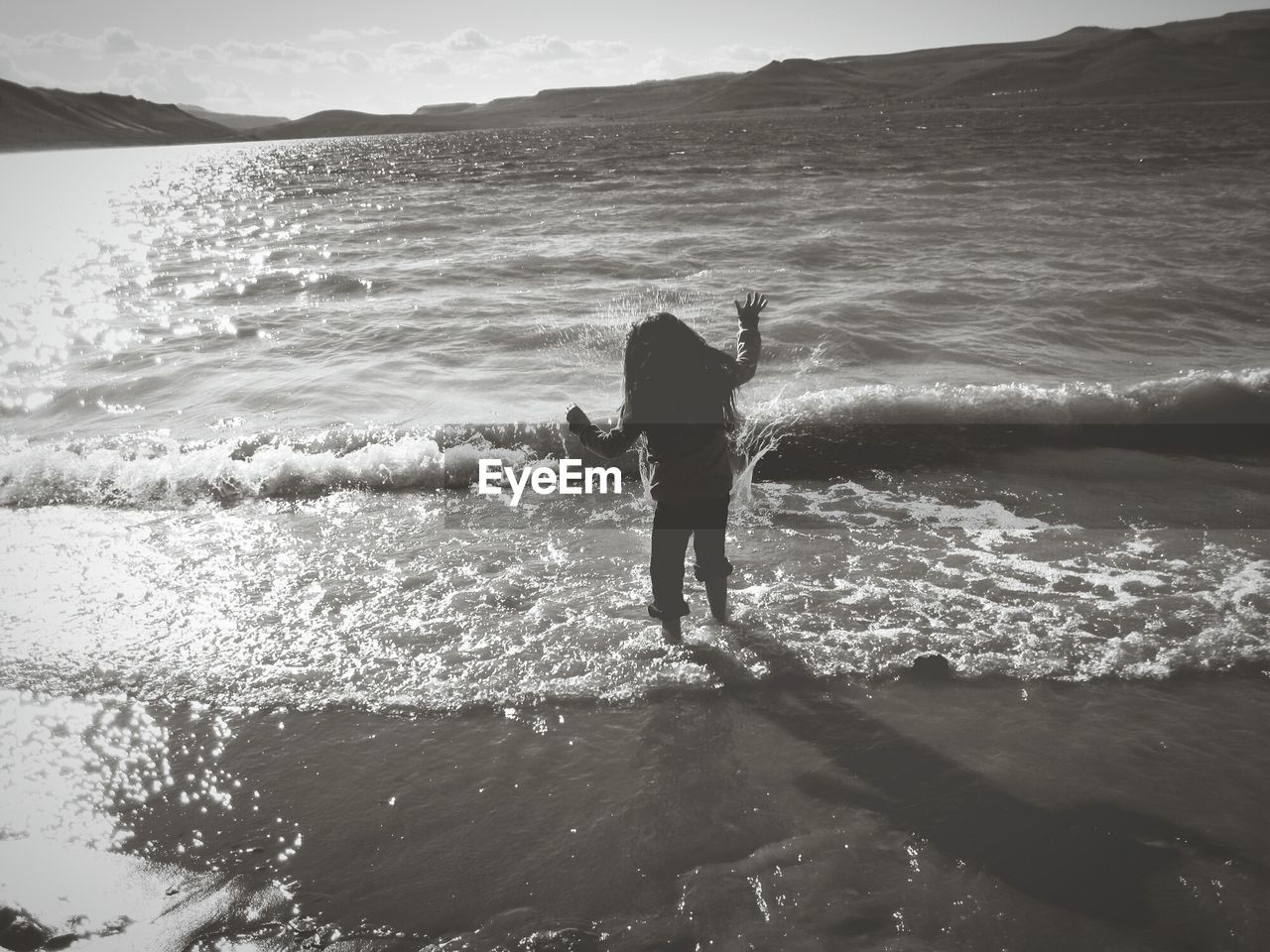 Rear view of playful girl standing on shore