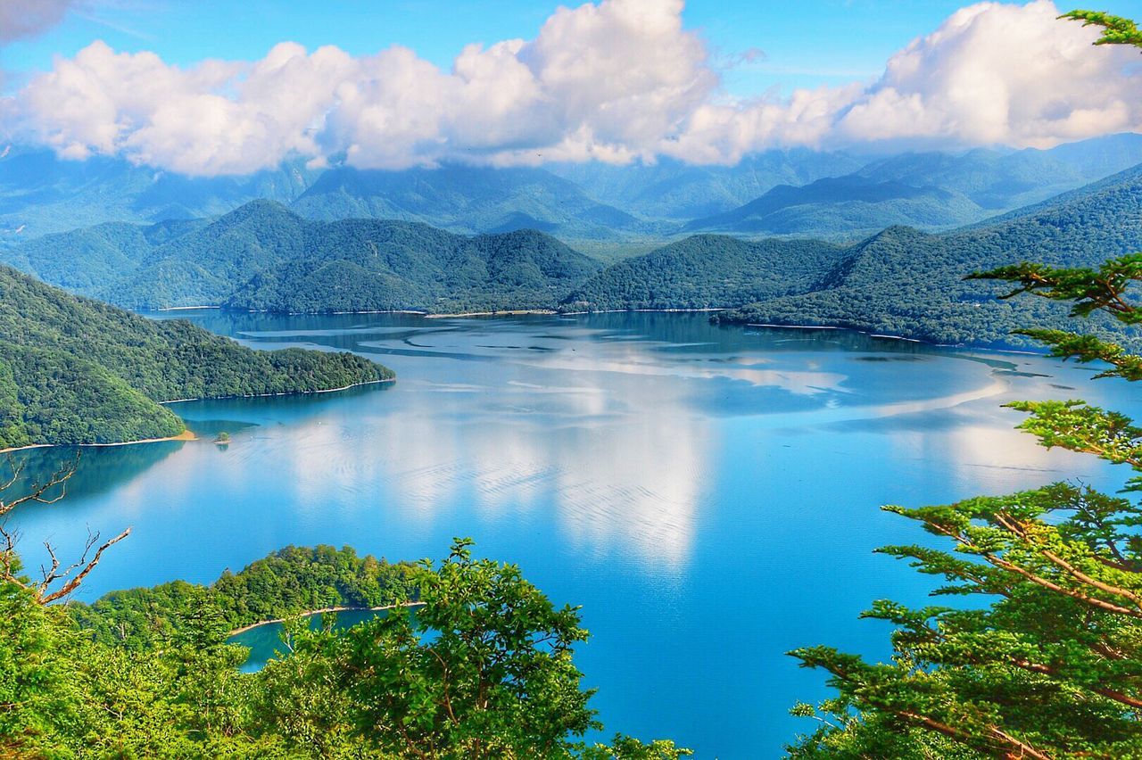 VIEW OF CALM LAKE SURROUNDED BY MOUNTAIN RANGE