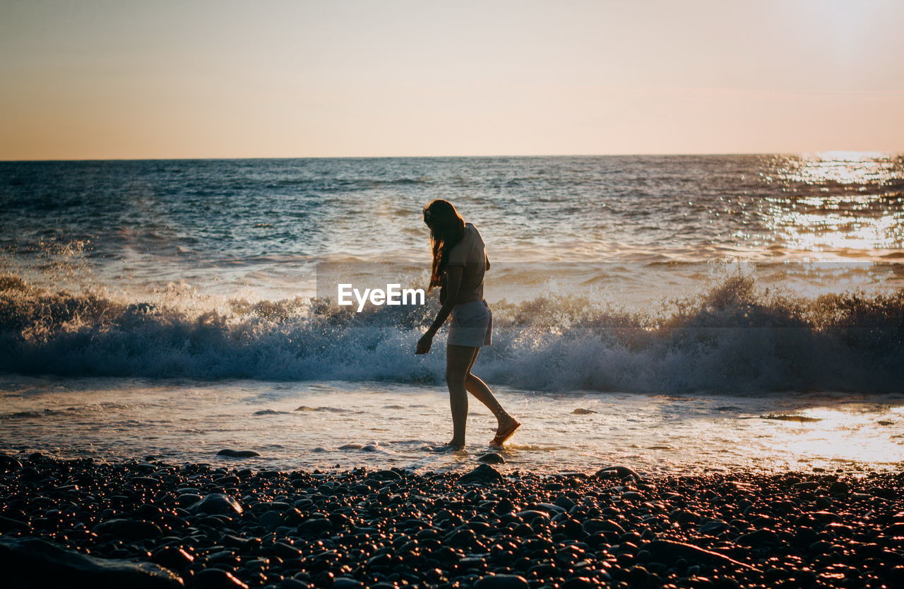 Brunette woman at the sea on sunset