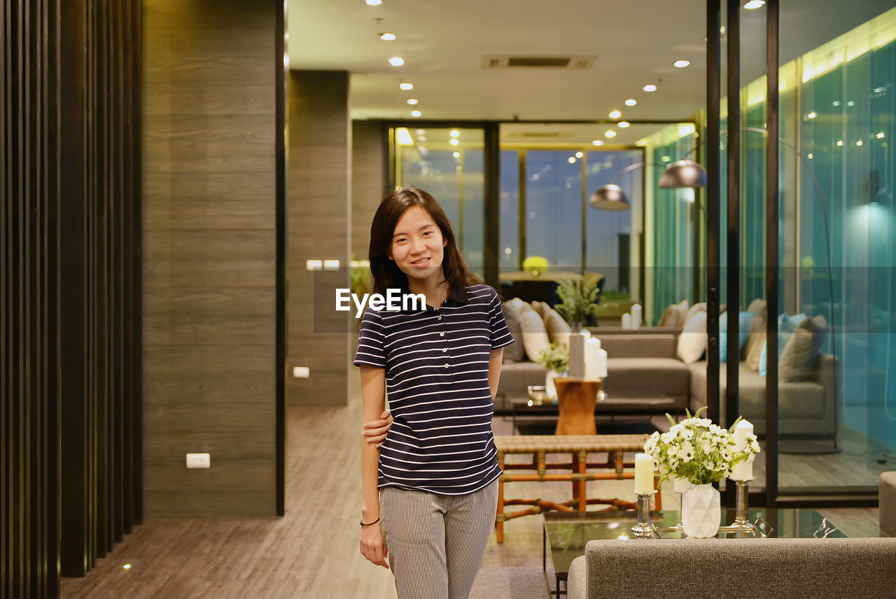 Portrait of woman standing in illuminated hotel room