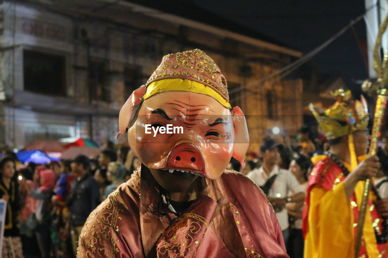 Portrait of woman wearing costume against people at night during festival