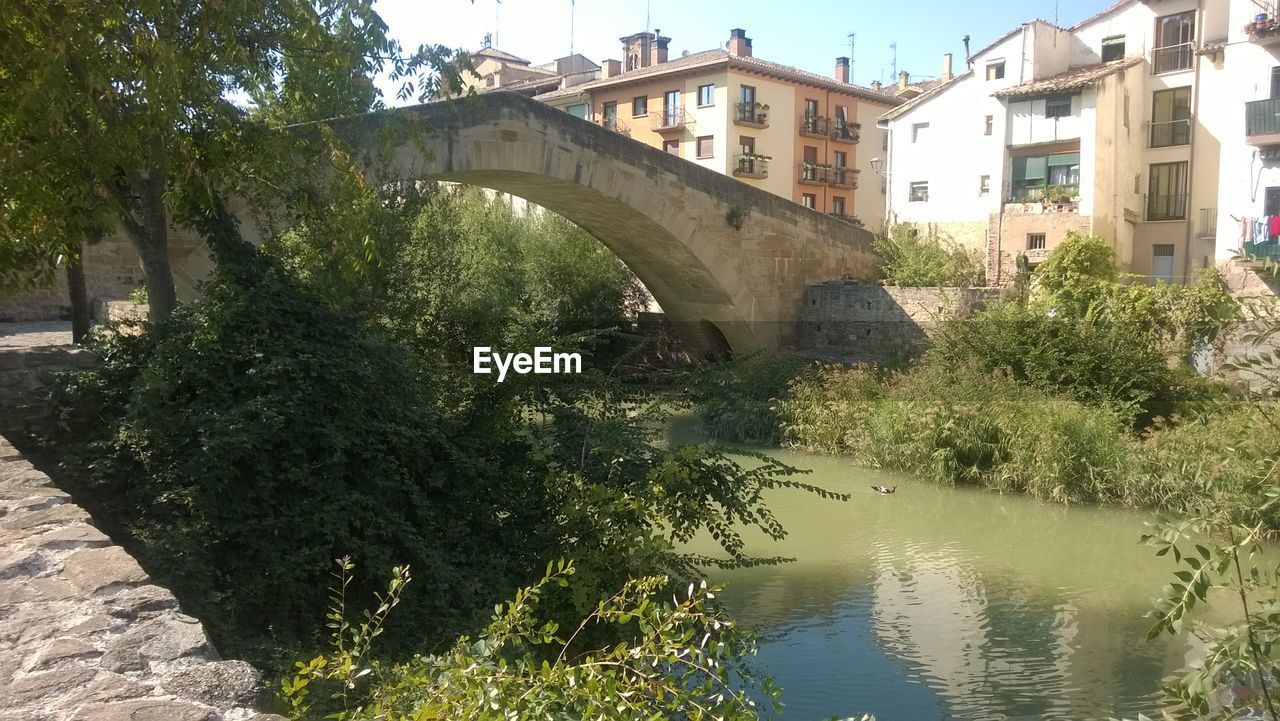 BRIDGE OVER RIVER WITH CITY IN BACKGROUND