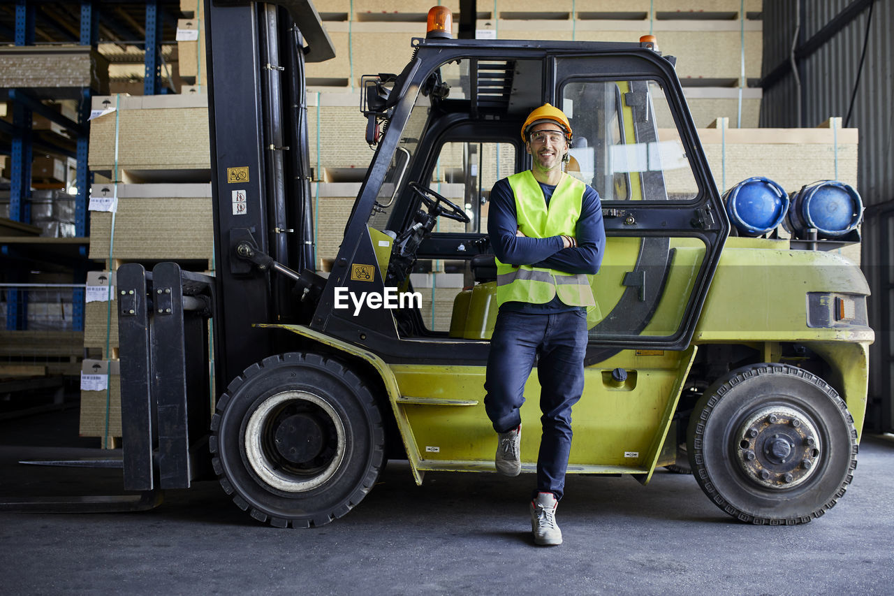 Portrait of confident worker at forklift in factory