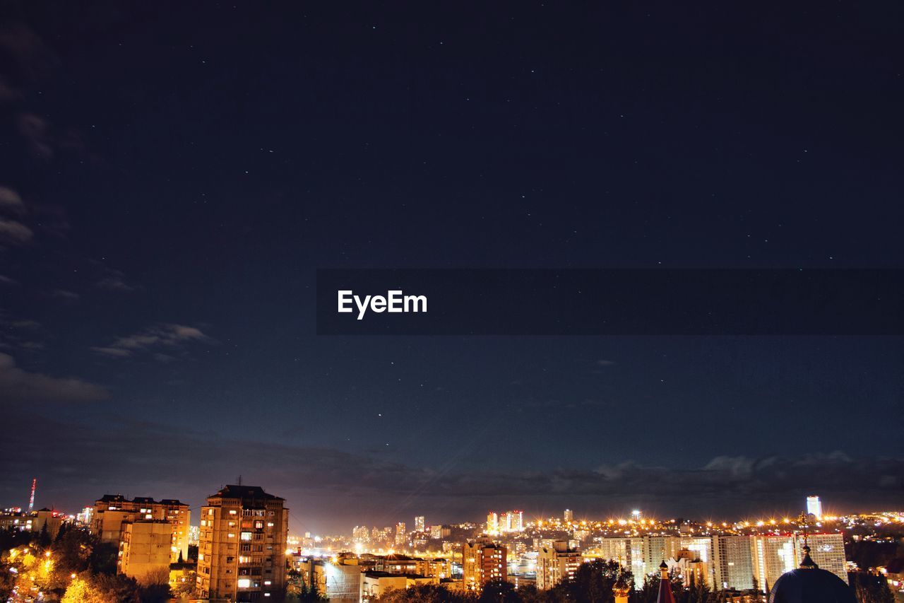 High section of illuminated cityscape against sky at night